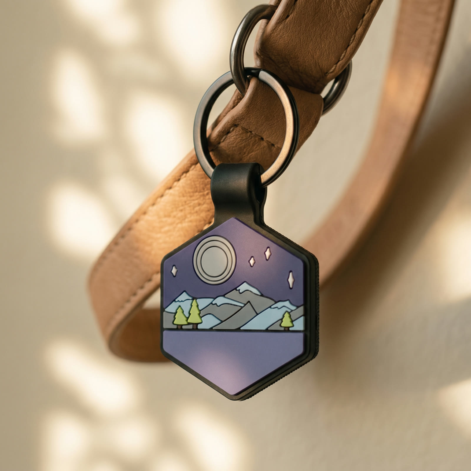 A close-up of a hexagonal silicone Tagling tag hanging from a leather collar, matte-black frame and illustrated silicone face visible.